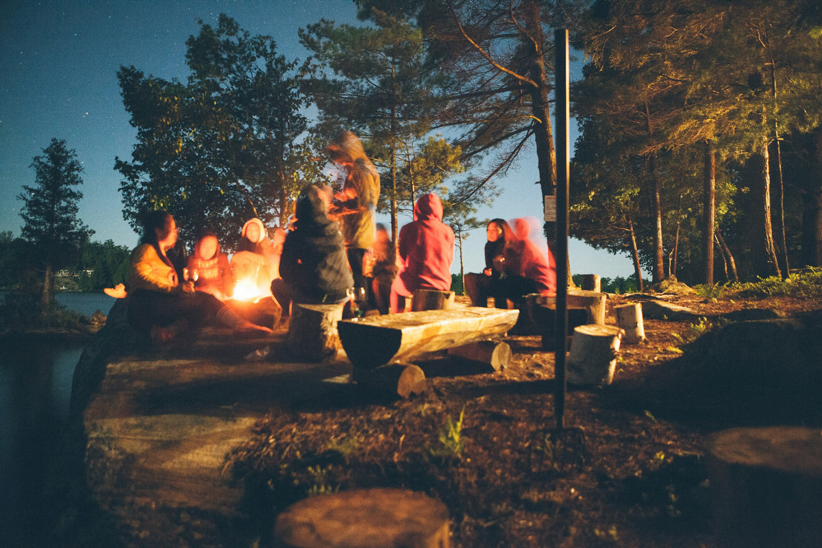 Grupo alrededor de una fogata en el bosque durante la noche — Ferrata Outdoor